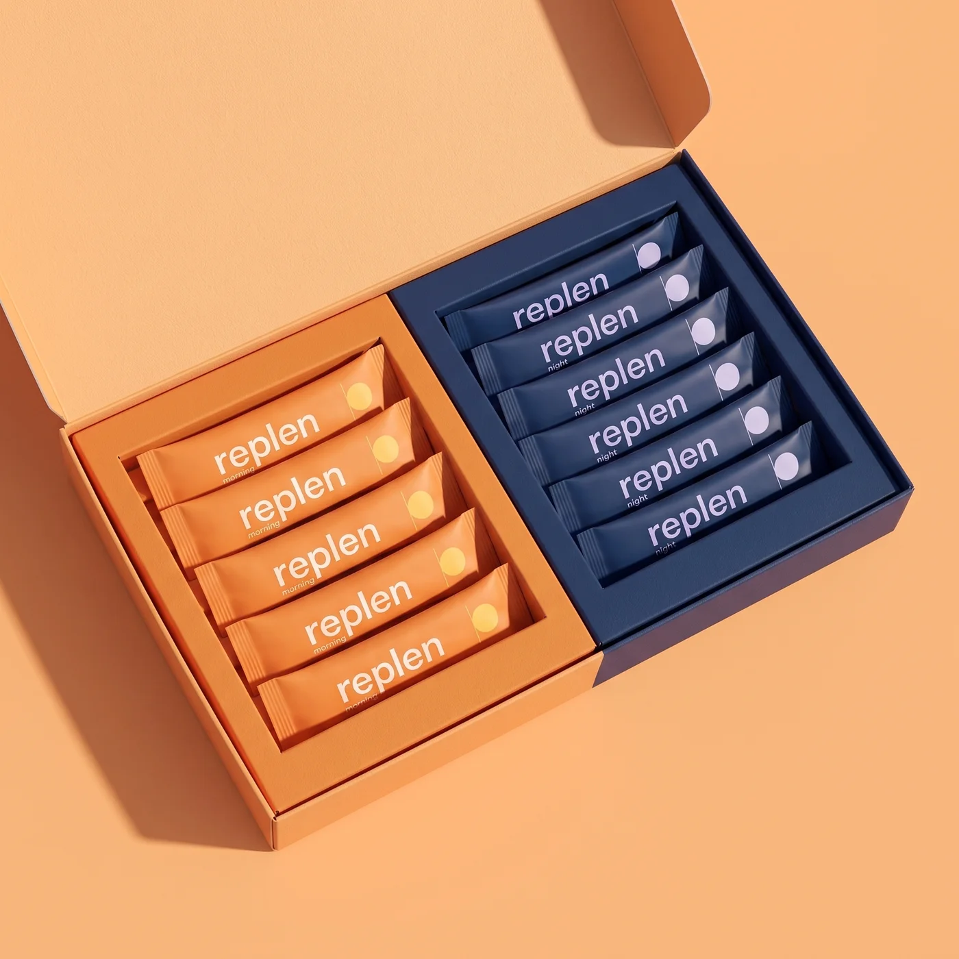 The open Replen box, half orange and half midnight blue, with rows of morning and night packs inside