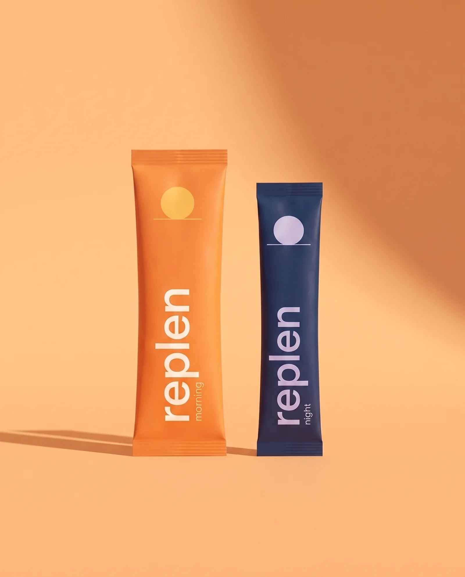 The two Replen packs: the orange morning pack with a small sun and the midnight-blue night pack with a small moon