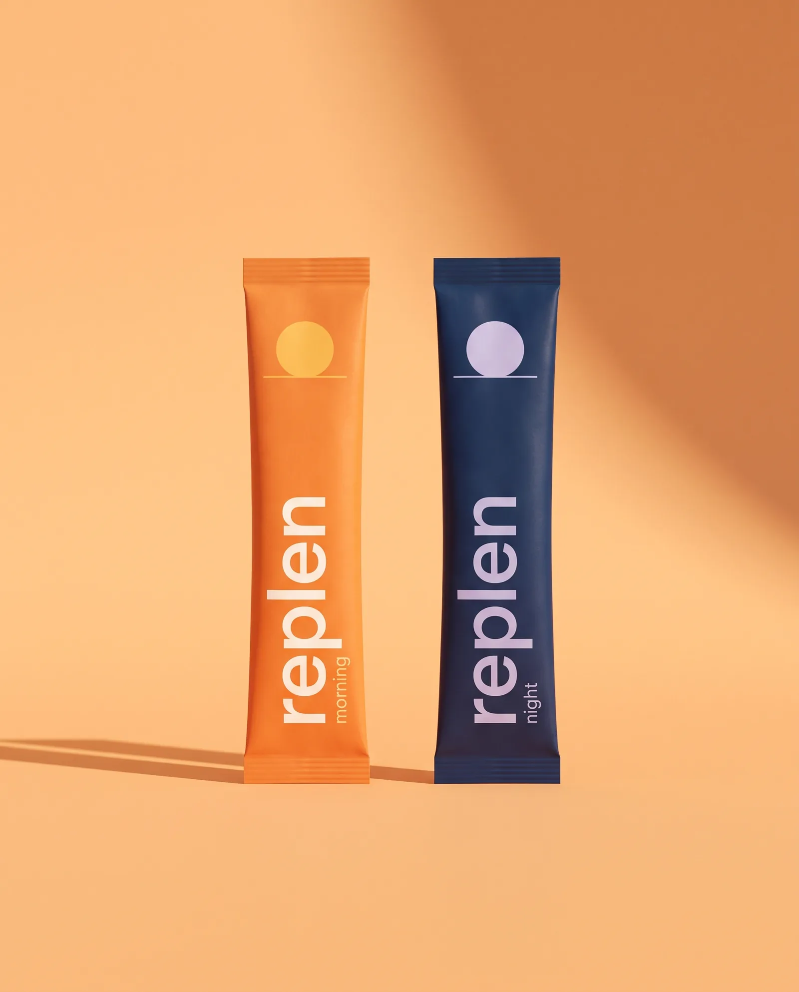 The two Replen sticks: the orange morning stick with a small sun and the midnight-blue night stick with a small moon