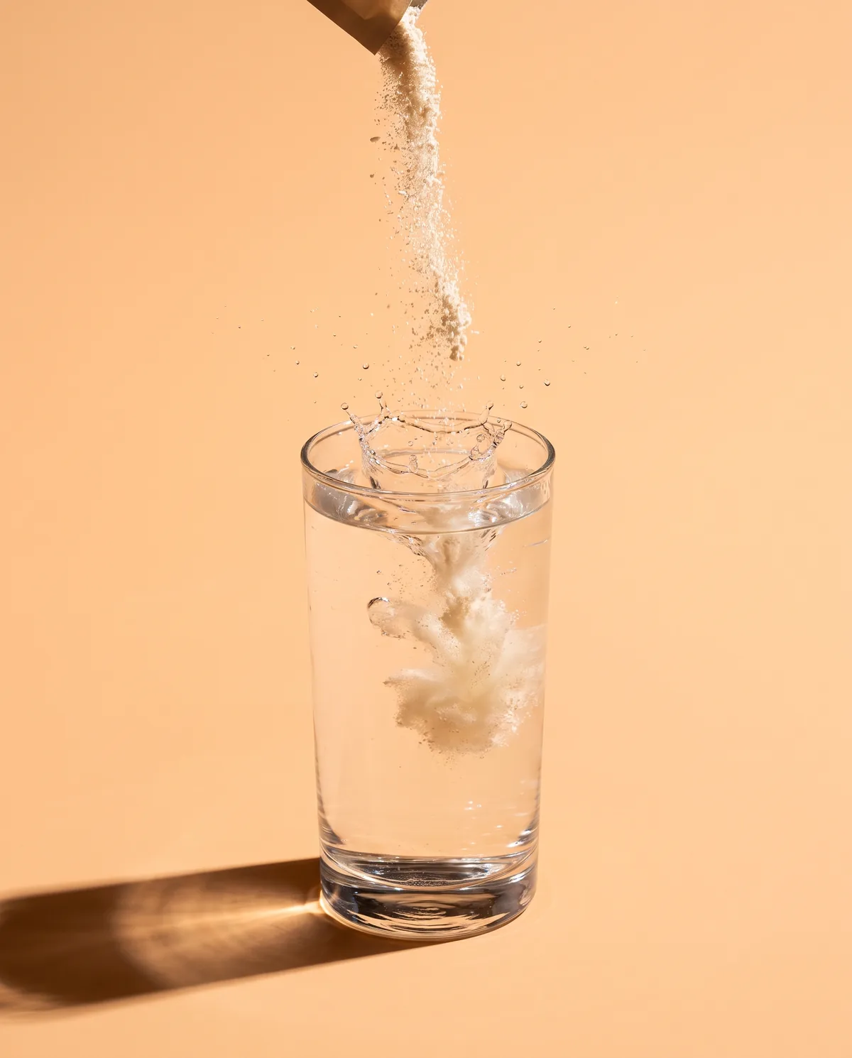 Powder pouring into a tall glass of water, caught at the moment of the splash